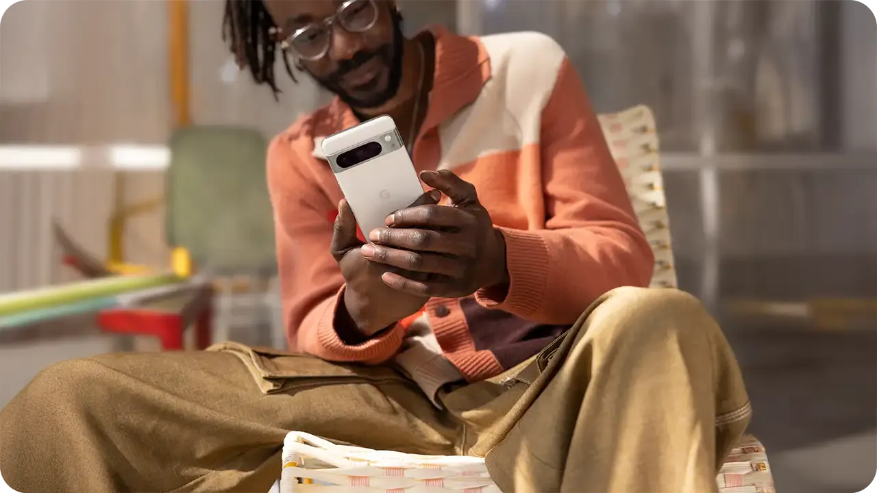 Ein Mann sitzt und benutzt sein Android-Smartphone.
