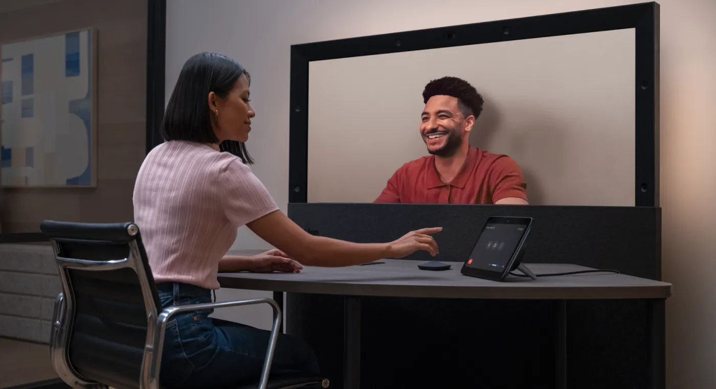 A carousel of images and videos shows the evolution of Google Beam devices over time.
A person gestures with their hands while chatting with a colleague during a Google Beam video meeting.