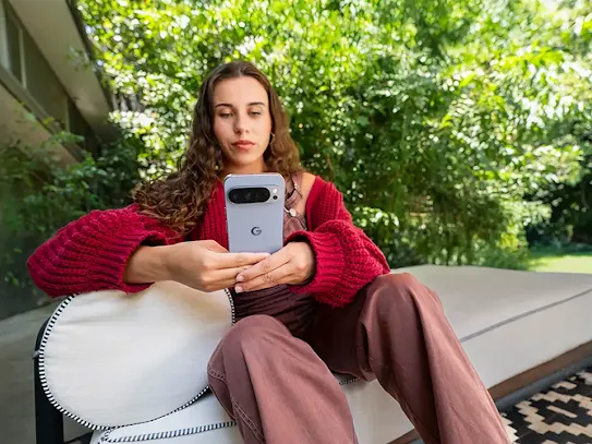 Woman using her phone outside, with trees in the background.