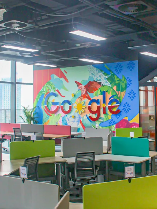 Google ロゴとさまざまなデスクが置かれたワークスペース。