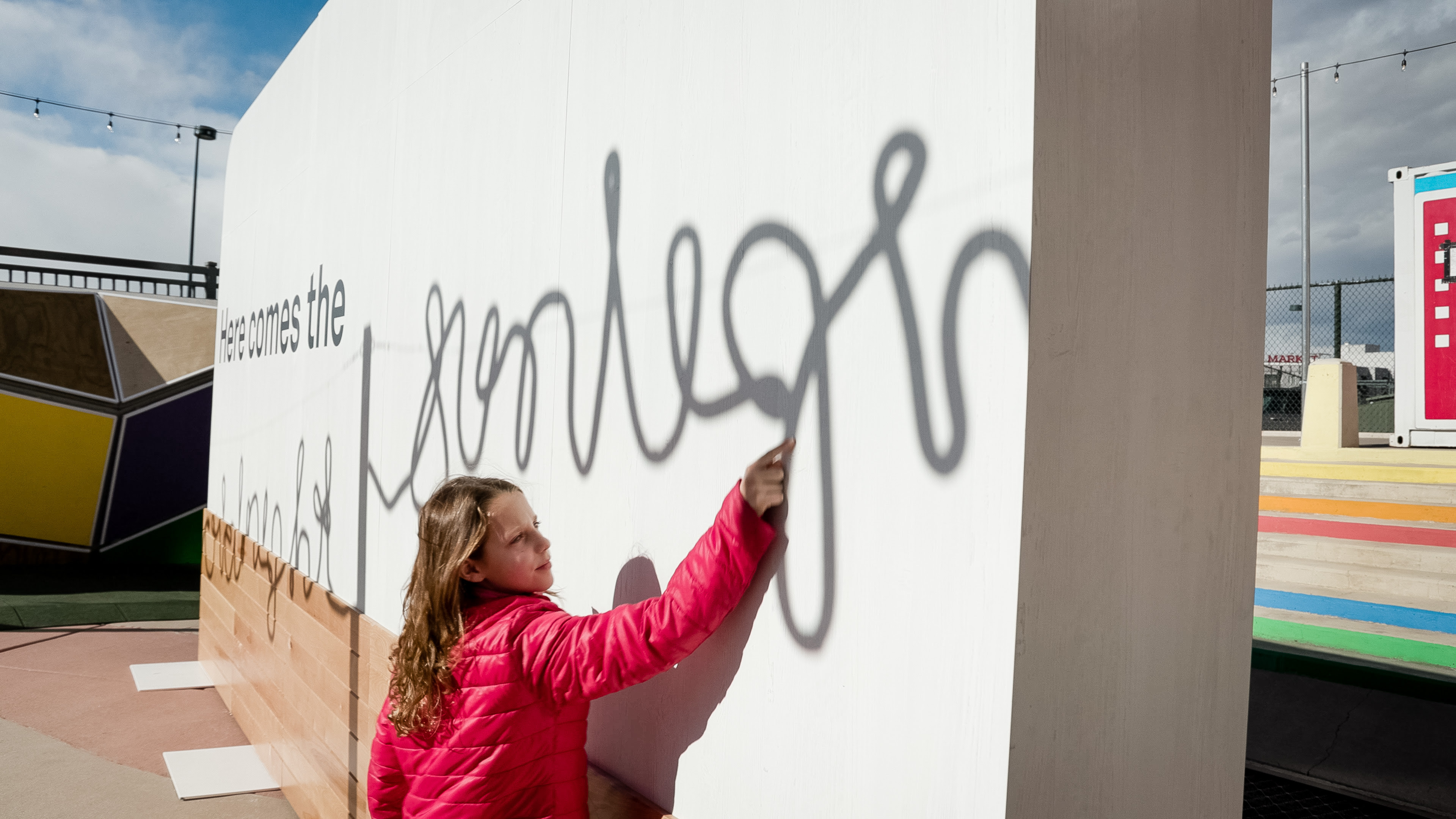 A young person engaging with a wall that's part of an experiential pop-up in downtown Denver to educate locals on the energy burden facing many neighbourhoods during the cold months