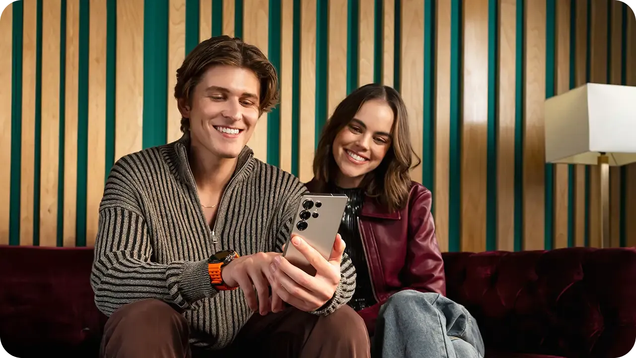 Man and woman sitting together looking at Android phone