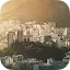 An aerial view of a dense city skyline with numerous apartment buildings situated at the foot of a large, sunlit mountain.