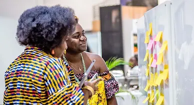 Two women examine a sticky note board at the event.