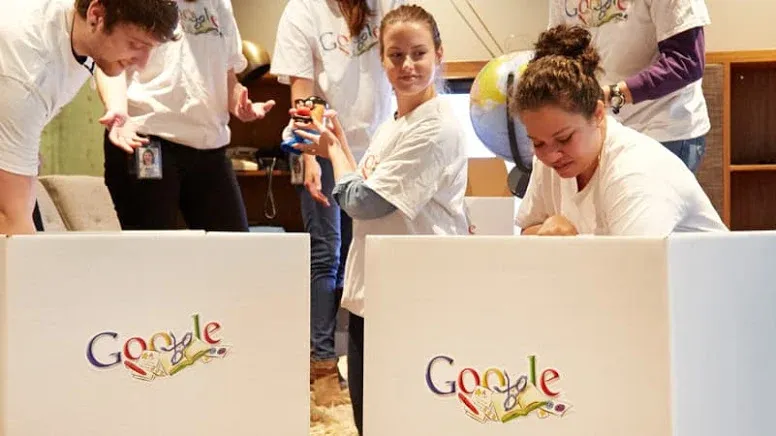 Group of volunteers wearing Google t-shirts working behind large white Google-branded collection boxes