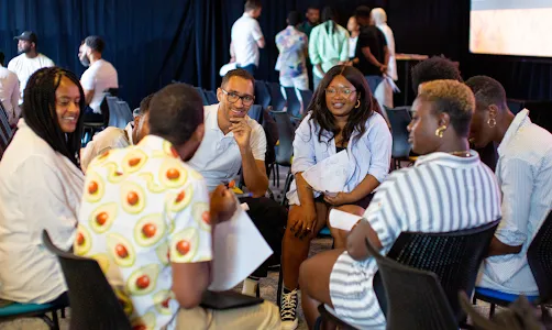 A team seated on a chair facing away from the camera, discussing.