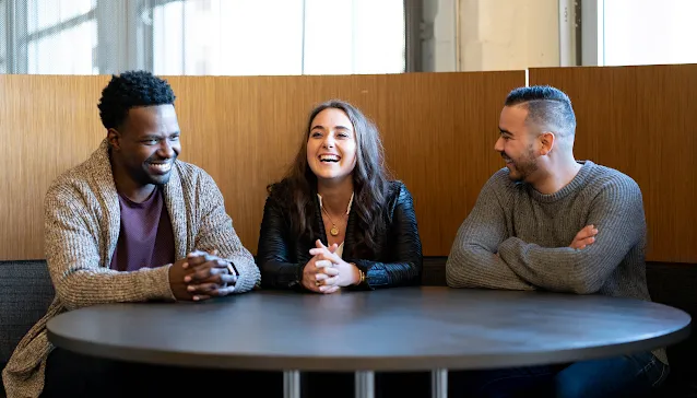 A lady is writing on a white board and looking at man.