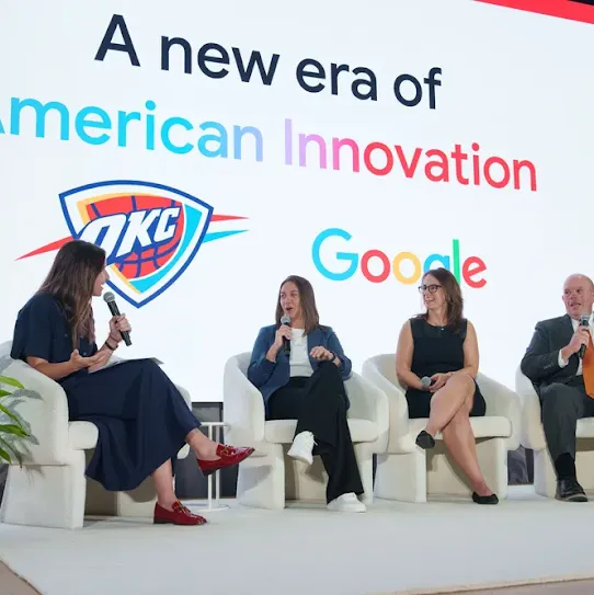A panel discussion taking place on a stage with four people seated in white armchairs. A screen behind them displays the text "A new era of American Innovation" above the OKC Thunder logo and the Google logo.