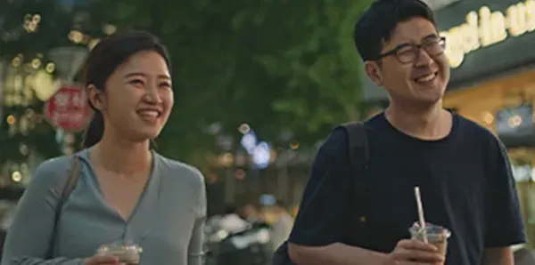 Founders, Suji and Han, are walking with drinks in their hands along a dimly lit sidewalk.