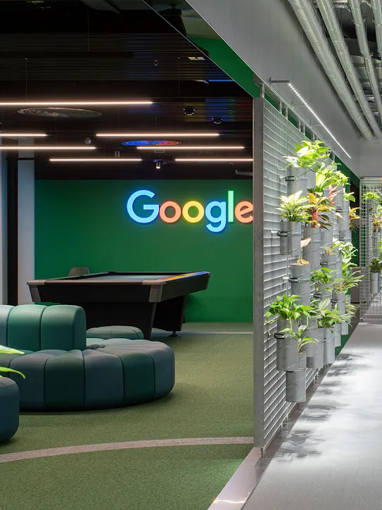 ソファと植物が置かれたワークスペースに Google ロゴが掲げられている。