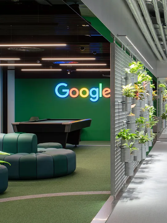 Un espace de travail avec le logo Google, des canapés et des plantes.