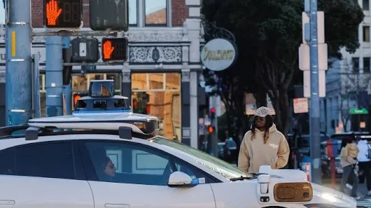 A waymo sits at a stop light in a city.