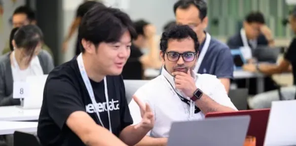 Two men at a conference collaborating in front of a laptop.