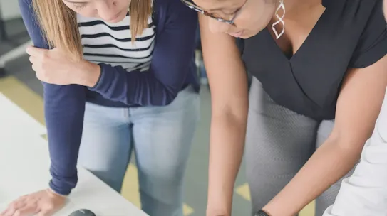 A photograph of students or professionals collaborating on a project, used to illustrate the Yduqs case study. The image represents the partnership's focus on digital transformation in education, showing how Yduqs utilizes Google Cloud and AI technology to personalize learning experiences and expand access to higher education for millions of students across Brazil.