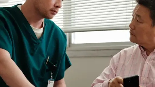 A doctor speaks with a man that's pointing at his phone