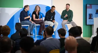 3 men and a woman sitting on chair holding mic on stage
