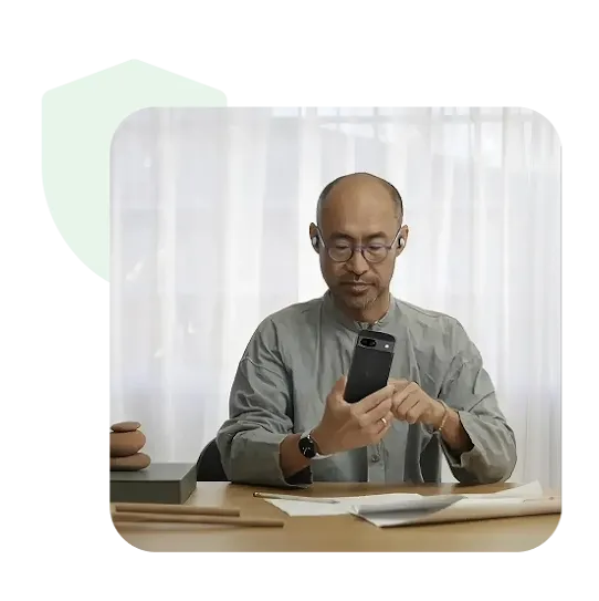 A male employee at a work desk conducting work on a mobile device.