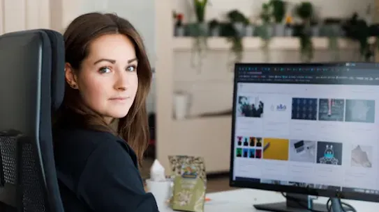 a woman operating a computer looking at the camera