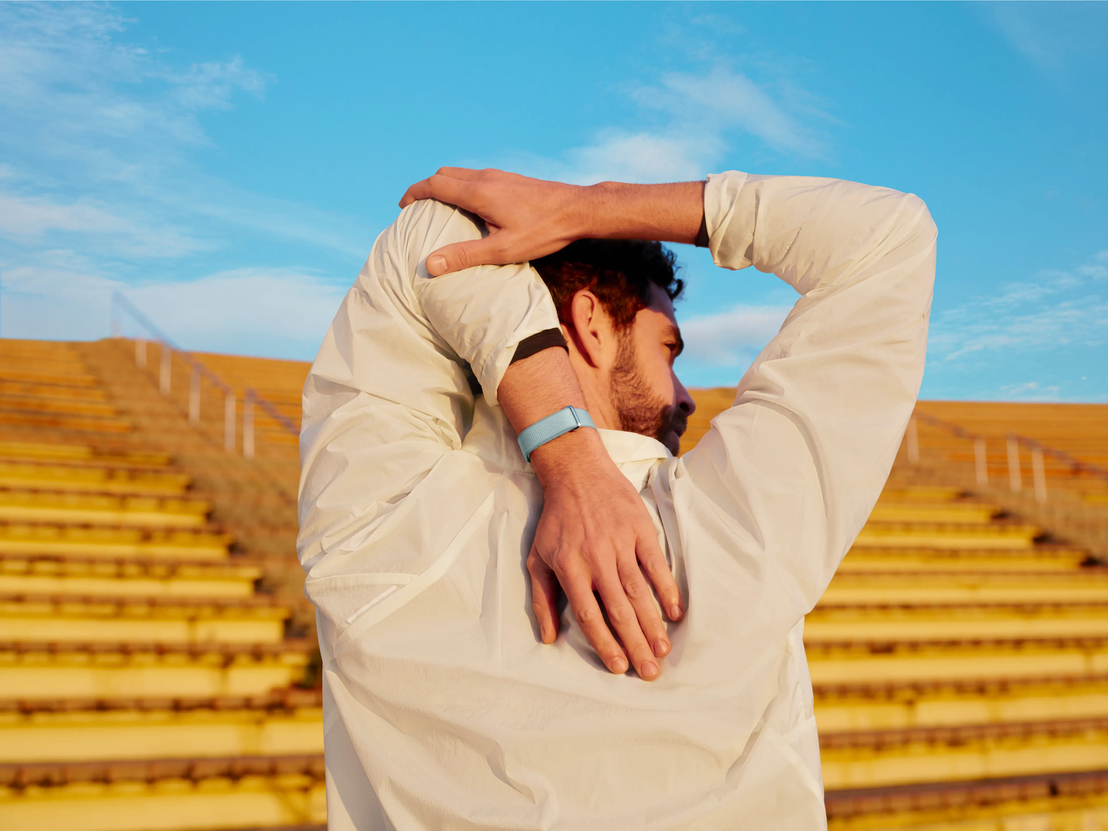 Image of man stretching wearing Google Fitbit Air. 