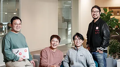 The Swit team are sitting around a couch smiling at the camera.