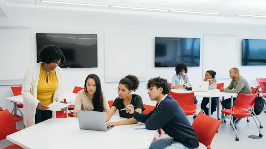 A group of people sitting around a computer. 