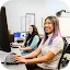 A young smiling woman with purple-tinted hair types on a keyboard while working at a computer in a modern classroom or office.