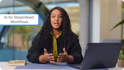 A woman with long curly dark hair sitting at a desk and speaking with hand gestures, with an open laptop, sticky notes, and a small potted plant in front of her. A blue text bubble in the top left corner reads "AI for Streamlined Workflows."