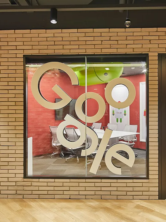 A view of a conference room from the outside. The Google logo is on the glass.