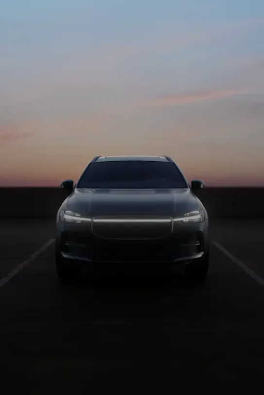 A car drives on a road at sunset.