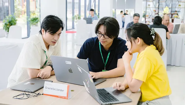 Three people seated around a laptop, collaborating and looking at the screen.