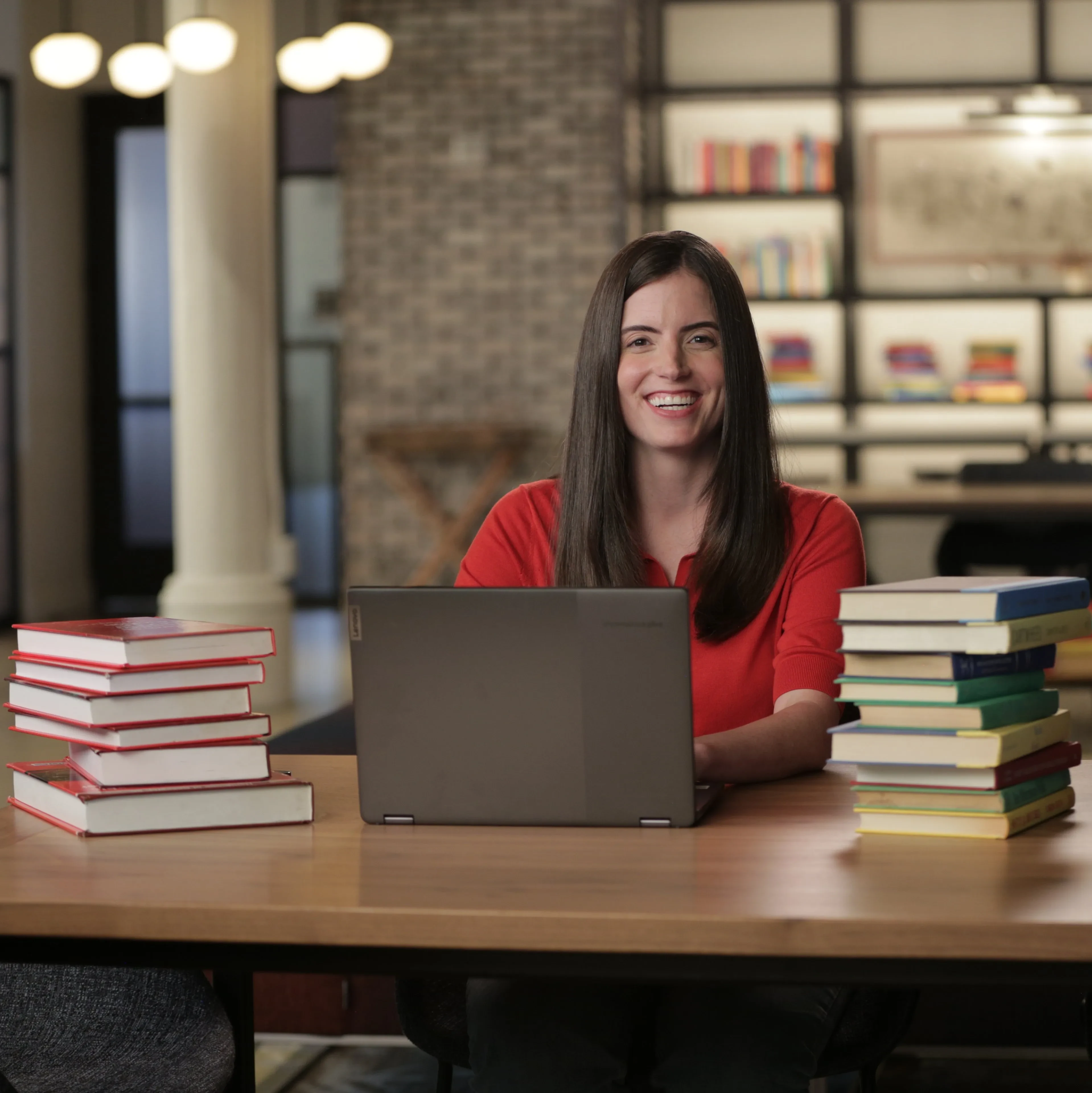 A student is sitting in a study hall, doing work on a laptop