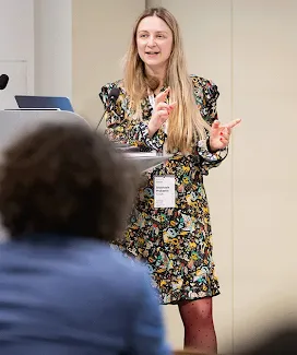 A smiling lady is hosting the event and presenting something.