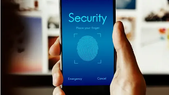 A hand holds a smart phone on which an ombré blue background is displayed. The words ‘security’ and ‘place your finger’ appear above a thumb print that indicates the biometric access protections available on this device.