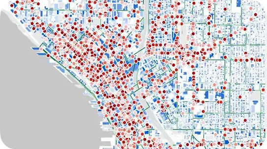 A 16:9 widescreen geographic data map visualization showing a coastal city grid in shades of blue and white. A high density of overlapping red, pink, and light orange dot indicators clusters heavily along the waterfront and major roadways, representing heat mapping or demographic data distribution.