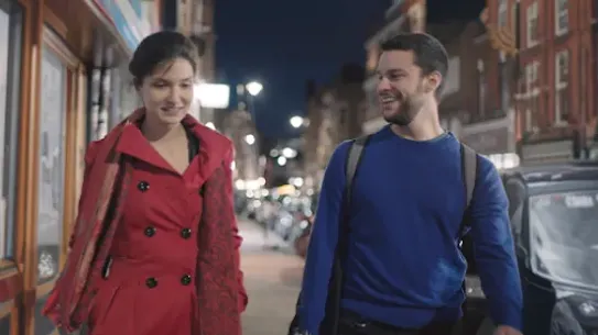 Founders, Elina and Adam, are walking along a sidewalk at night.