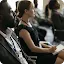 A diverse group of professionals wearing name tags sitting in an audience and listening to a presentation.