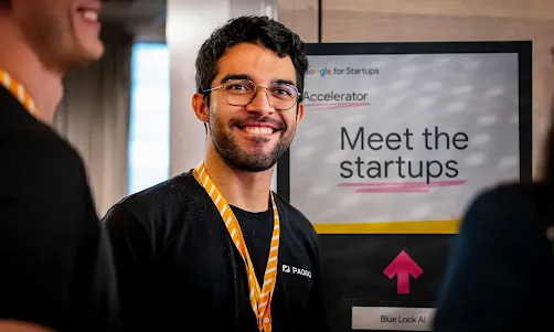 An event attendee standing next to a large display screen that reads 'Meet the Startup'.