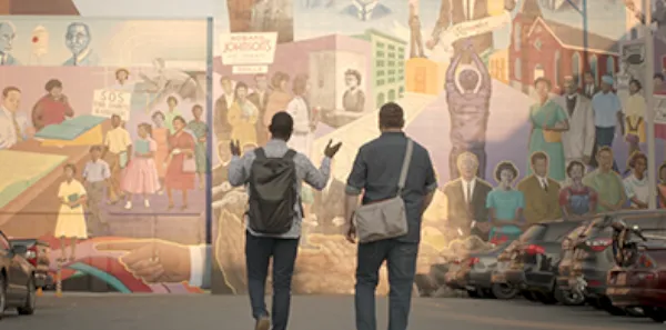 Founders, Justin and Bernard, are walking in front of a mural.