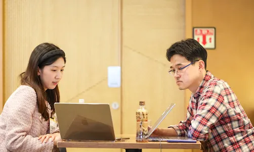 A woman sharing her laptop screen with a man.