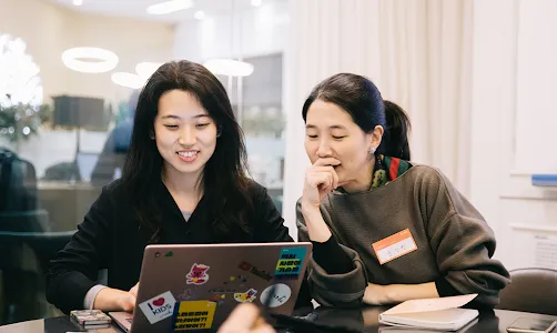 Two ladies are working on a laptop.
