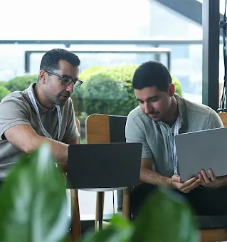 Man working on a laptop while talking to a colleague.