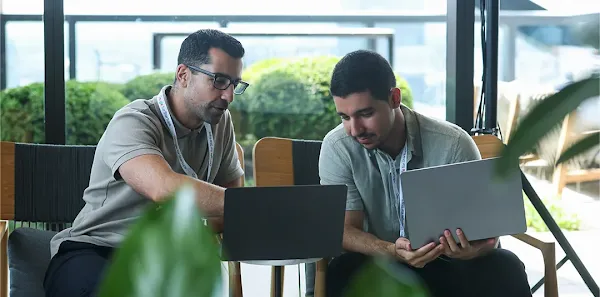 Man working on a laptop while talking to a colleague.
