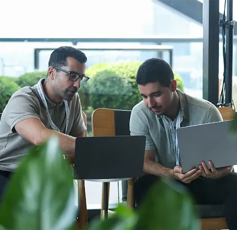 Man working on a laptop while talking to a colleague.