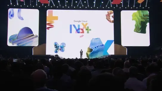 man stands on stage at conference with screens behind him that say Google Cloud Next