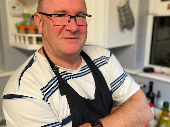 Photograph of Gav in his kitchen with arms crossed.