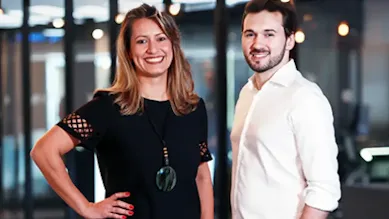 Founders Tatiana and Everton pose in front of an office space