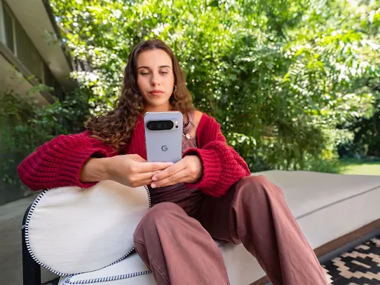 Eine Frau benutzt ihr Smartphone draußen, mit Bäumen im Hintergrund.