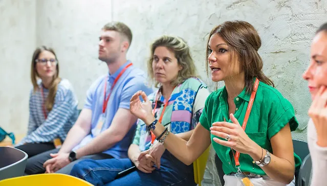 Three women conversing, One women wearing green dress is in focus.