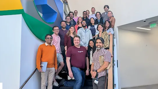 Adults standing in front of Google sign smiling