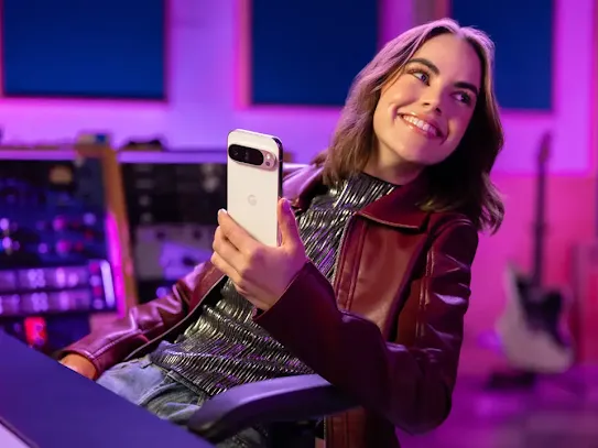 Woman sitting in a sound studio holding an Android phone